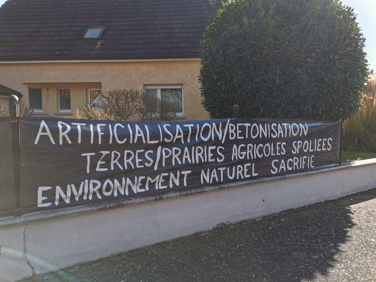Banderole « Artificialisation/Bétonnisation — Terres/Prairies agricoles spoliées — Environnement naturel sacrifié » à Schœnau