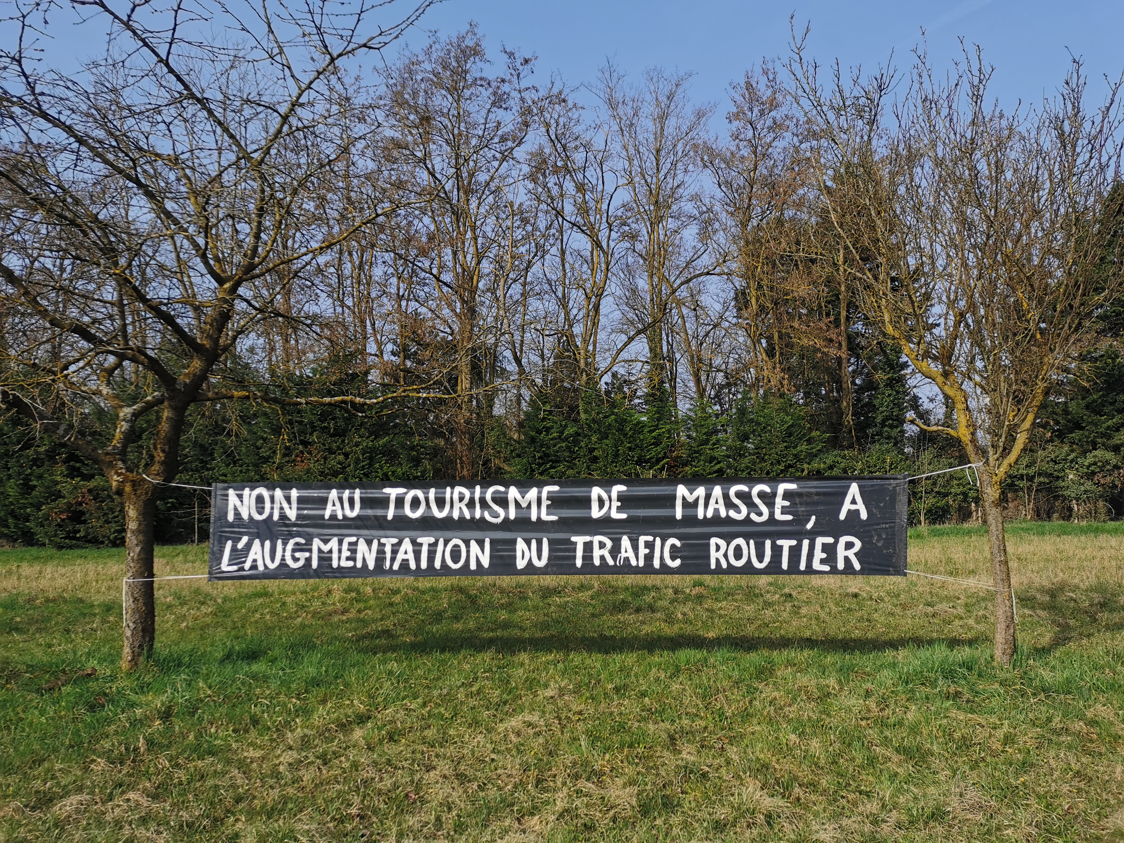 Banderole « Non au tourisme de masse, à l'augmentation du trafic routier » dans un verger à Wittisheim