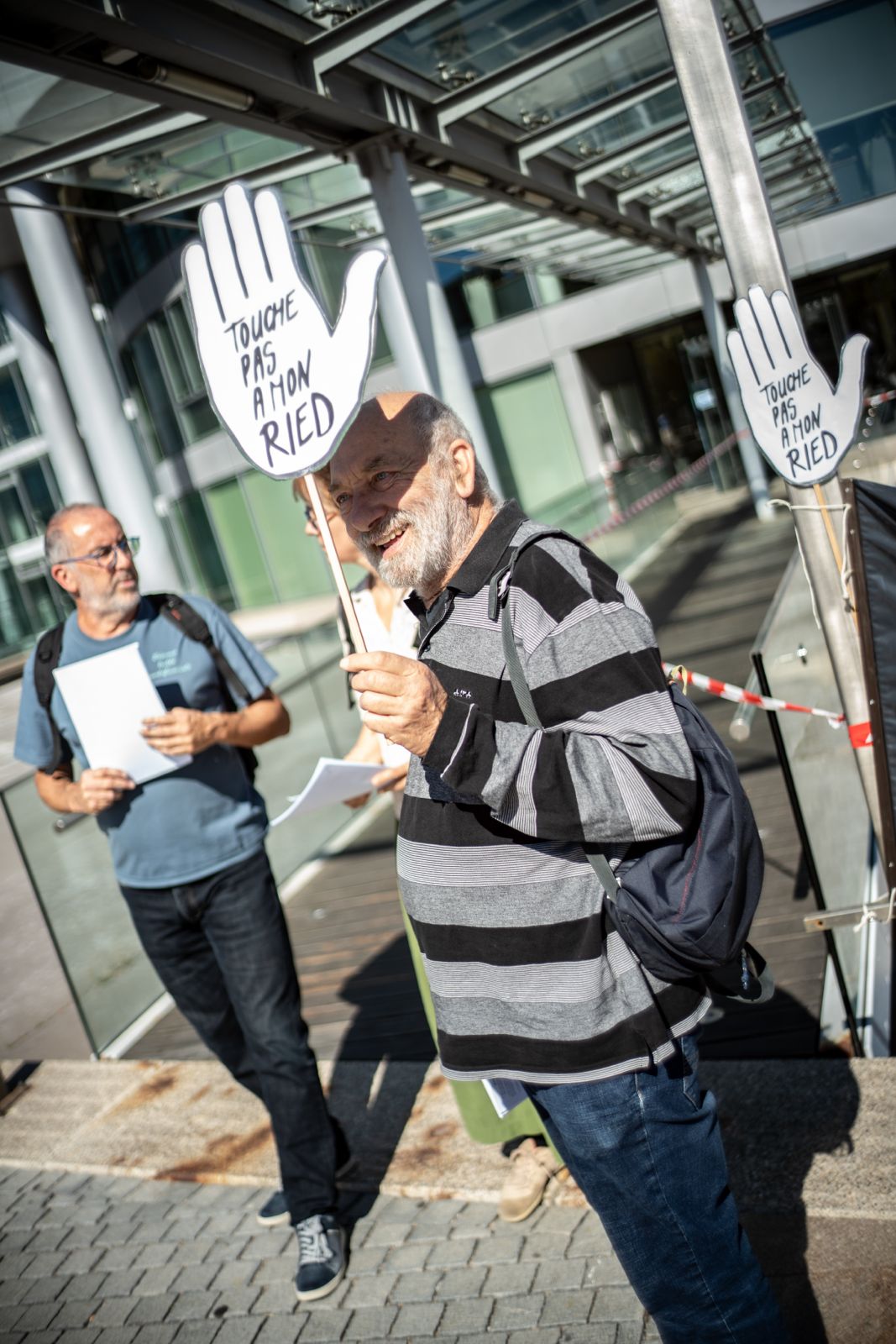 Un membre du collectif brandit une pancarte en forme de main « Touche pas à mon Ried »